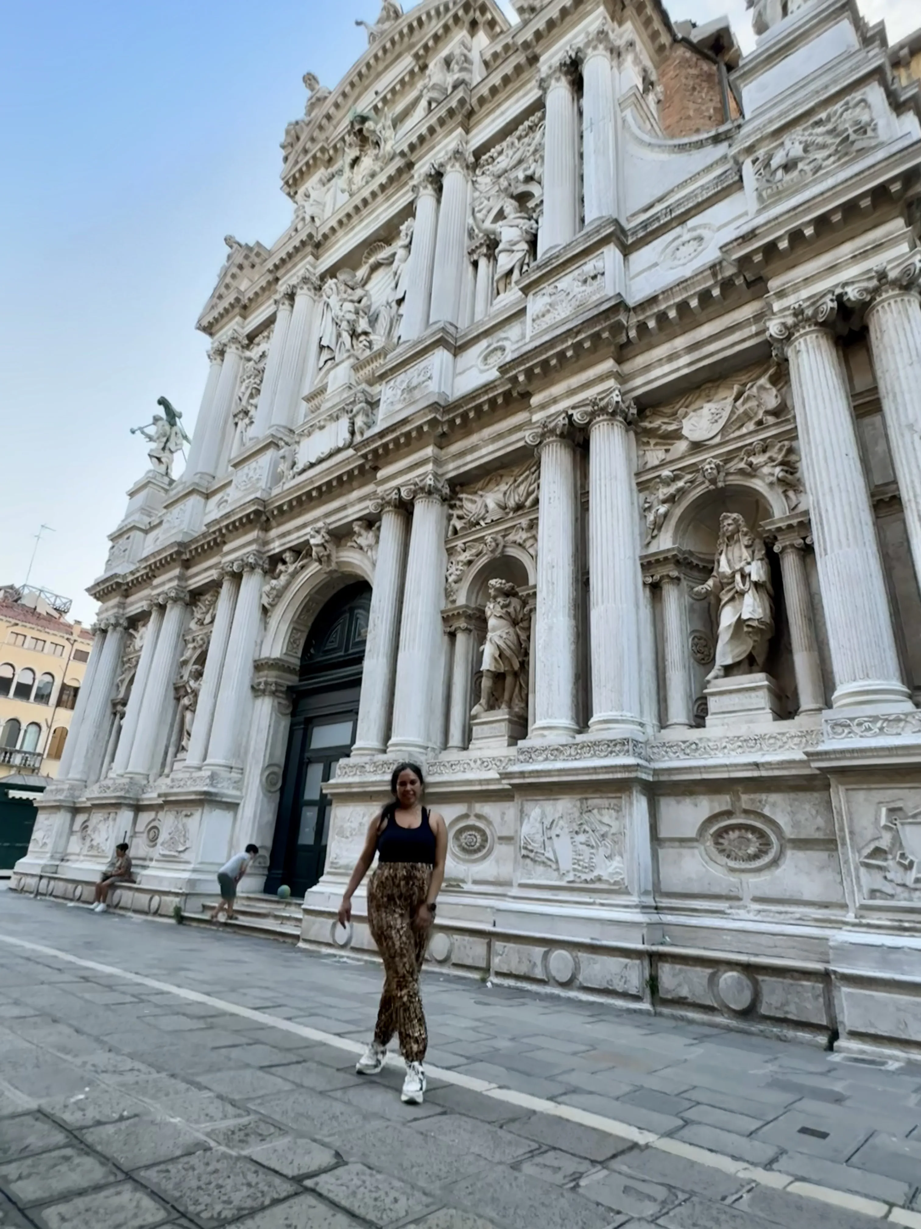 Woman in stylish outfit posing in front of ornate historical building.