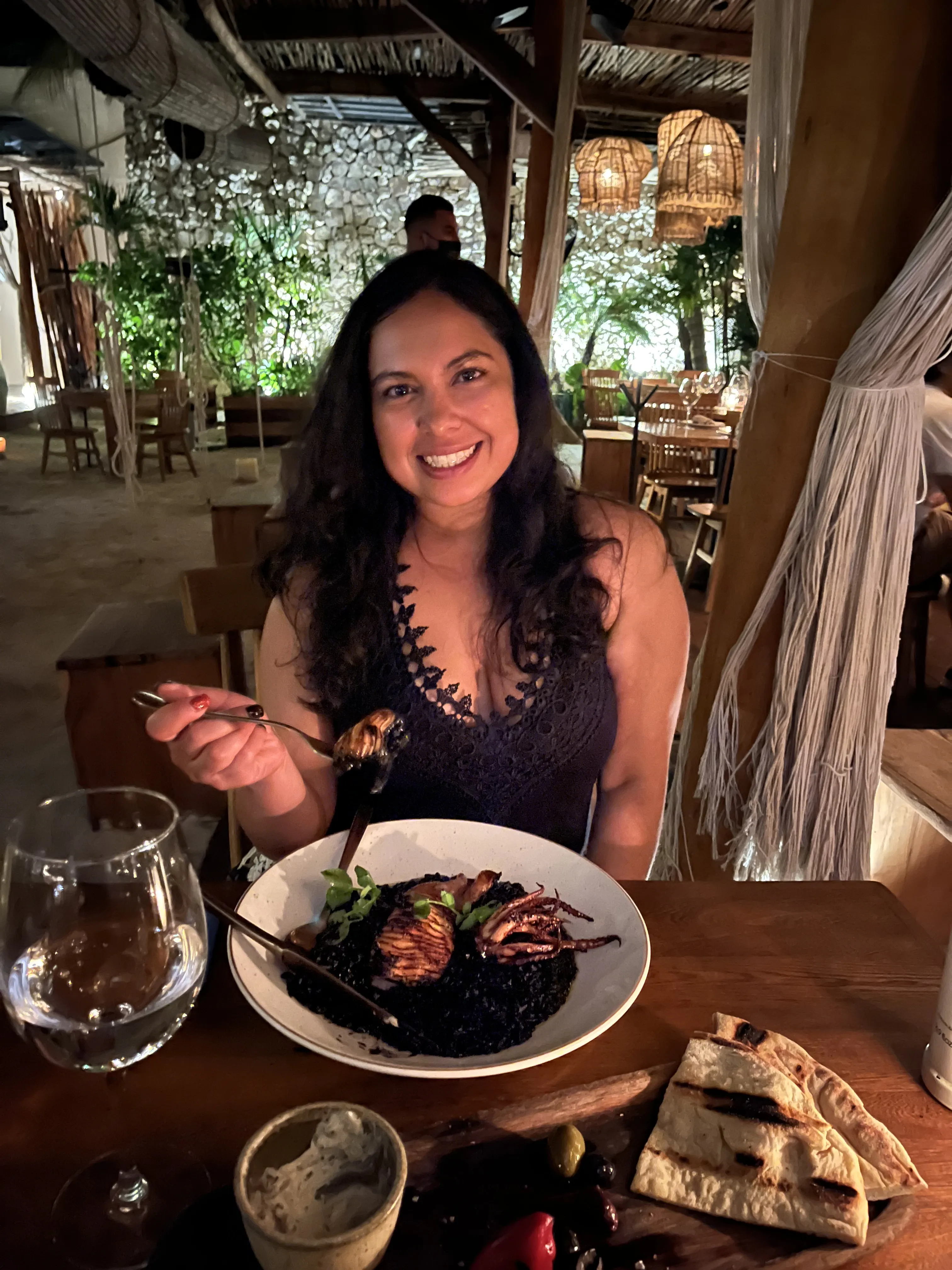 Woman enjoying a plate of seafood pasta in a cozy restaurant setting.